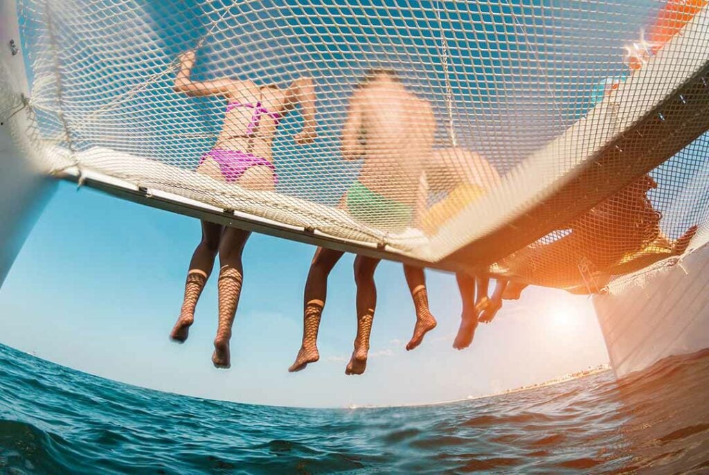 People sitting on netting of a Catamaran, Spain